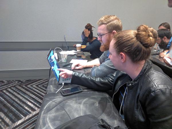 A woman pointing something out in a laptop screen. The laptop is being operated by a man.